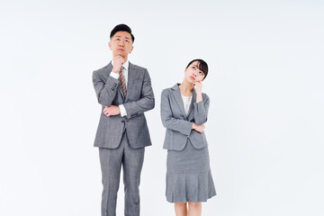 疑問を感じるポーズをするスーツ姿の男女