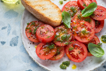 Close-up of fresh red tomatoes served with basil oil, green basil and grilled ciabatta, horizontal shot, selective focus