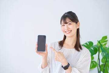 Fototapeta premium スマートフォンを指差す若い女性