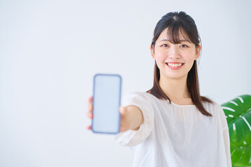 Naklejka premium スマートフォンの画面を見せる若い女性