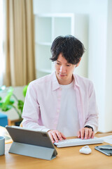 Obraz premium 部屋でパソコンの操作をする若い男性