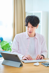 Fototapeta premium 部屋でパソコンの操作をする若い男性