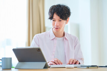部屋でパソコンの操作をする若い男性