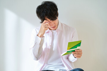 通帳を見て、がっかりする若い男性