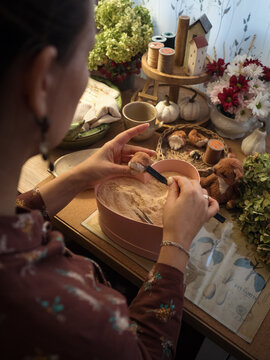 Woman stuffing Teddy toy with sawdust at her cozy desk