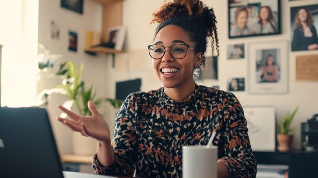 A mixed-race woman in casual attire participating in a video team call, with houseplants and art in her home office, representing a flexible work culture - Powered by Adobe