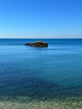 Calm sea, rock and clear blue sky at morning