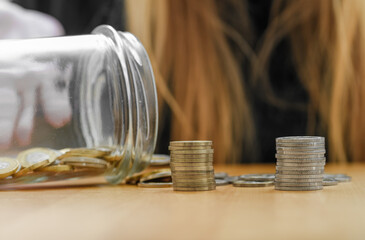 Stos monet wysypany że szklanego słoika, oszczędności na drobne przyjemności 