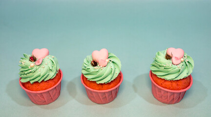 Cupcakes with sprinkles. Cupcake on a mint color background. Pink cupcake with mint cream and pink heart