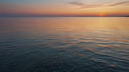 Obraz premium A tranquil sea at sunrise, with soft pastel colors blending into the horizon and calm ripples on the water
