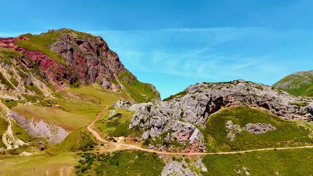 Beautiful rocks with scarce greenery on sunny day. Drone rising over the mountainous landscape at the backdrop of blue sky.