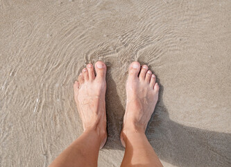 Pretty woman legs in pink shorts relaxing on sand and seashore
