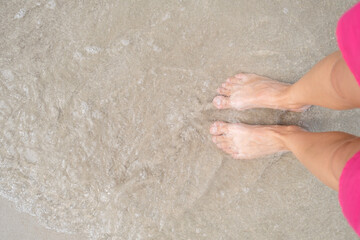 Pretty woman legs in pink shorts relaxing on sand and seashore