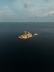 Aerial image of Isolated rock island on the middle of the ocean at golden hour