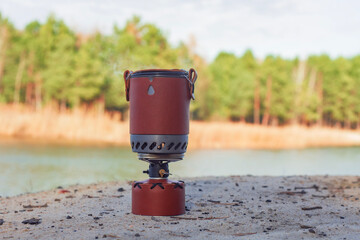 Tourist stove gas for camping and recreation in forest on the background of nature.