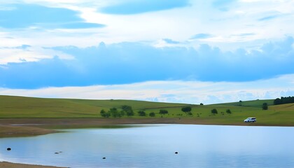 Tranquil rural lake with verdant grass and azure sky, picturesque scenery.