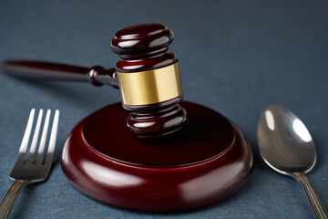Judges gavel with fork and spoon on a white background with copy space, close-up. Sanitary inspection, food law and justice concept