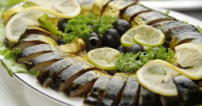 dried sturgeon cut into pieces on a plate, fish slices with lemon and olives