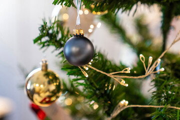 Christmas composition, gold and silver baubles, bows, animals, bells, lit garlands on a festive xmas fir tree against the decorative brick wall background. Copy space. Winter holidays concept.