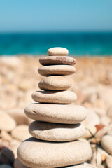 stack of rocks one above the other creating valance in an abstract imagen  on a beautiful beach with blue water in the back ground. holiday and vacation photography.