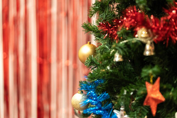 Christmas composition, gold and silver baubles, bows, animals, bells, lit garlands on a festive xmas fir tree against the decorative brick wall background. Copy space. Winter holidays concept.