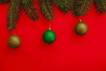 red christmas background. Minimalist Christmas arrangement with fresh evergreen branches and golden pinecones on a vibrant red background, perfect for holiday designs.