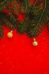 red christmas background. Minimalist Christmas arrangement with fresh evergreen branches and golden pinecones on a vibrant red background, perfect for holiday designs.