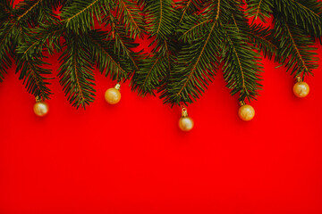 red christmas background. Minimalist Christmas arrangement with fresh evergreen branches and golden pinecones on a vibrant red background, perfect for holiday designs.