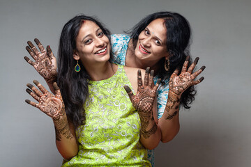 Two joyful Indian women show their beautiful henna designs, captured during the Karva Chauth...