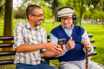 Portrait of happy grandfather and grandson in park. They are spending time together and having fun....