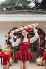 Candy Cane Christmas Cheer: A joyful young woman, dressed in a festive red dress, holds a giant candy cane over her head, radiating Christmas cheer.