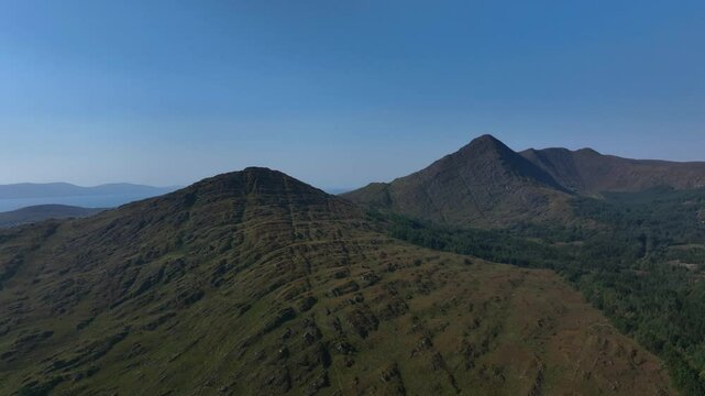 Sugarloaf, Caha Mountains, County Cork, Ireland, September 2024. Drone pushes forward towards the majestic mountain peaks under a cloudless sky with natural beauty in a peaceful rugged wilderness.
