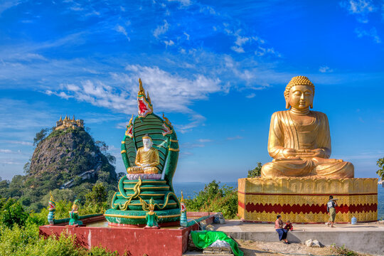 Buddha in front of Popa mount, Myanmar on a sunny summer day.
