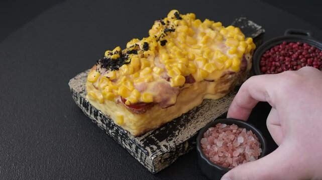 Sandwich with brioche, meat, melted cheese, corn, salt, spices and herbs on a dark concrete background