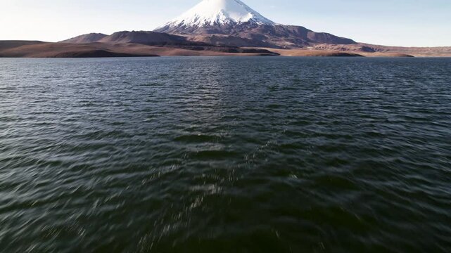 Aerial Drone Footage Showcases The Stunning Parinacota Volcano In Lauca National Park, Chile. Filmed On A Sunny Autumn Day, The Camera Glides Over The Lake, Revealing Waves And Majestic Scenery.