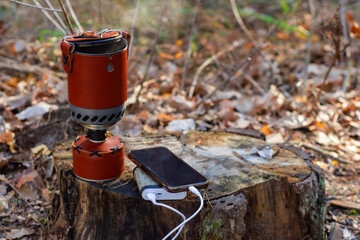 Charge your smartphone while traveling with the Powerbank. The portable charger charges your phone with a camping gas burner in the background.