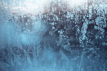 Blue winter background with frost pattern on the window. Beautiful frosty drawing.