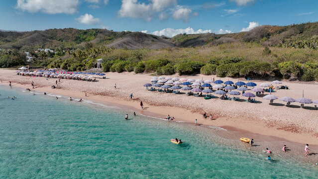 Warm day at Kenting Baishawan beach with sun umbrellas and people enjoying the water and sand