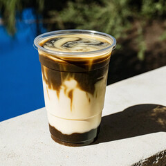 Iced caramel macchiato in a plastic cup, showing the beautiful swirls of coffee, milk, and caramel isolated