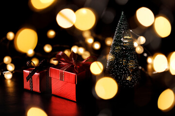 Miniature Christmas tree with red present boxes on black background.