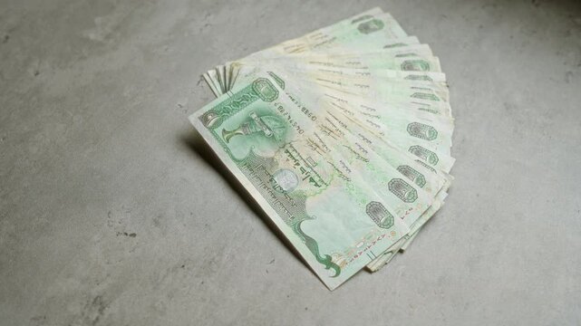 United arab emirates currency dirhams arranged in a fan-like pattern on a concrete surface.