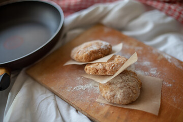 Homemade vegan patties placed on a rustic wooden board with parchment paper, styled in a cozy kitchen setting. Warm natural light highlights the texture, ideal for food photography or plant-based meal