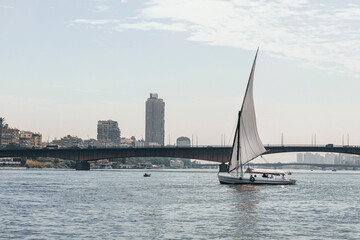 sailboat with tourists on a river walk sails along the Nile River in the center of Cairo among the skyscrapers and attractions.