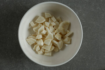 Finely chopped parsley root in a white bowl.