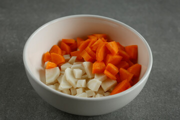 Finely chopped parsley root and carrot in a white bowl.