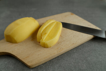 Sliced potatoes on a cutting board with a knife beside them.