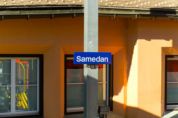 Fototapeta premium Sign with pole at railway station of mountain village of Samedan in the Swiss Alps on a sunny autumn day. Photo taken November 15th, 2024, Samedan, Switzerland.