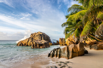 Granite rocks and palm trees on the scenic tropical sandy Anse Patates beach, La Digue island, Seychelles
