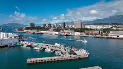Fototapeta premium Coastal view of Hualien harbor showcasing boats and city skyline under a bright blue sky