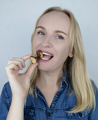 Prevention of thyroid disease. Woman holding a brazil nut in the shape of a thyroid gland. Nut rich...